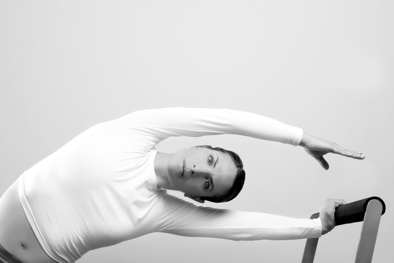 A woman in white shirt doing yoga pose.