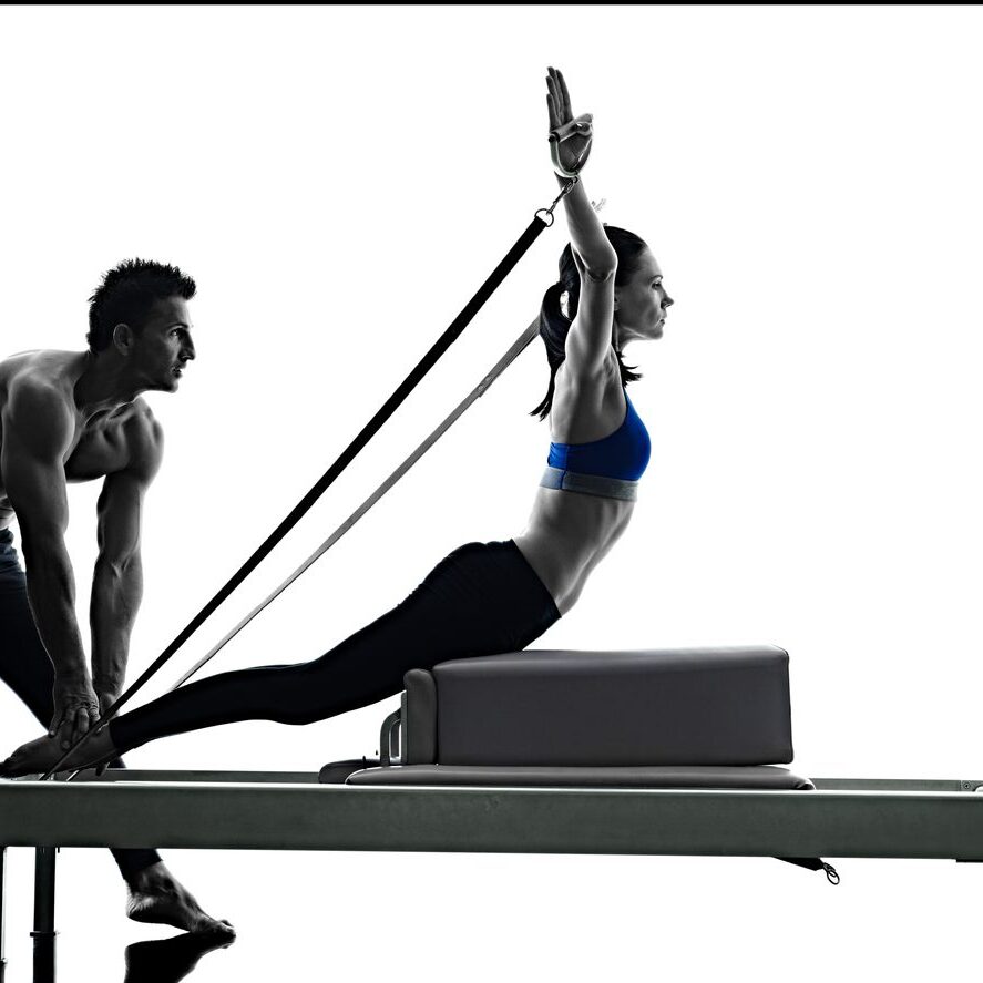 A man and woman are working out on the reformer.